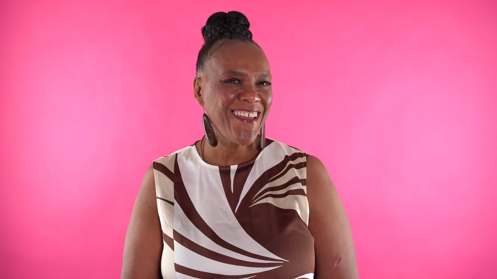 A woman smiling in front of a bright pink background