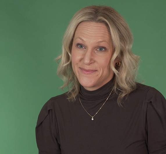 Emily Smith, Founder of Emily Smith Coaching sits in front of a green background.