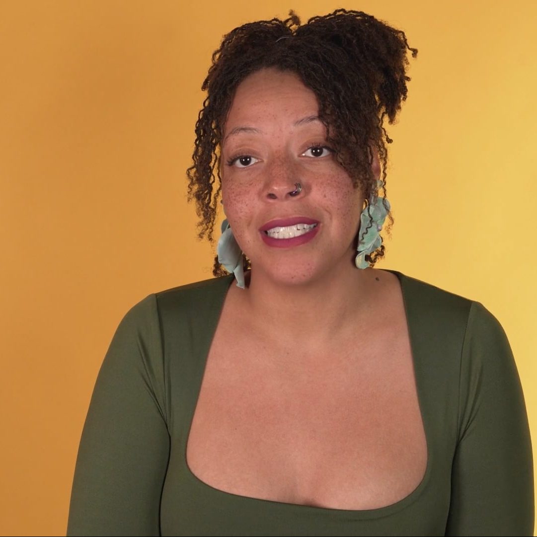 Tonika Goss smiling in front of a yellow background.