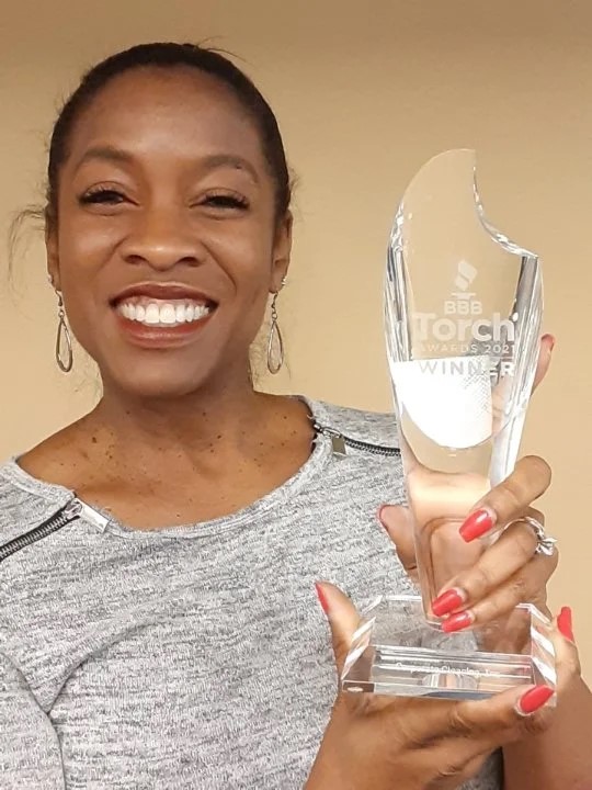 Emily Smith, Founder of Emily Smith Coaching sits in front of a green background.
